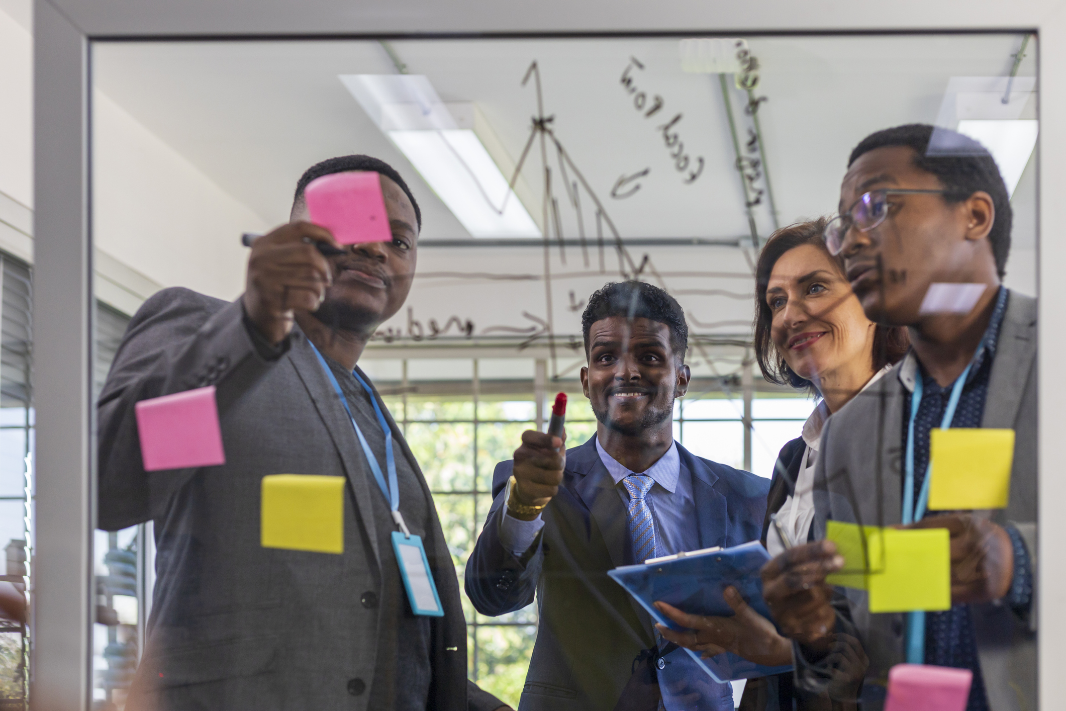 Team of African American executive worker is brainstorming on current financial trend while writing on board to explain to each other for diversity business